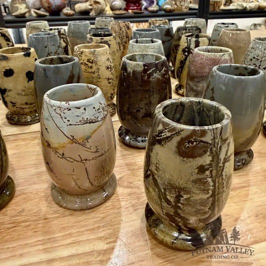 Collection of stone cups with unique textures and colors on a wooden surface.