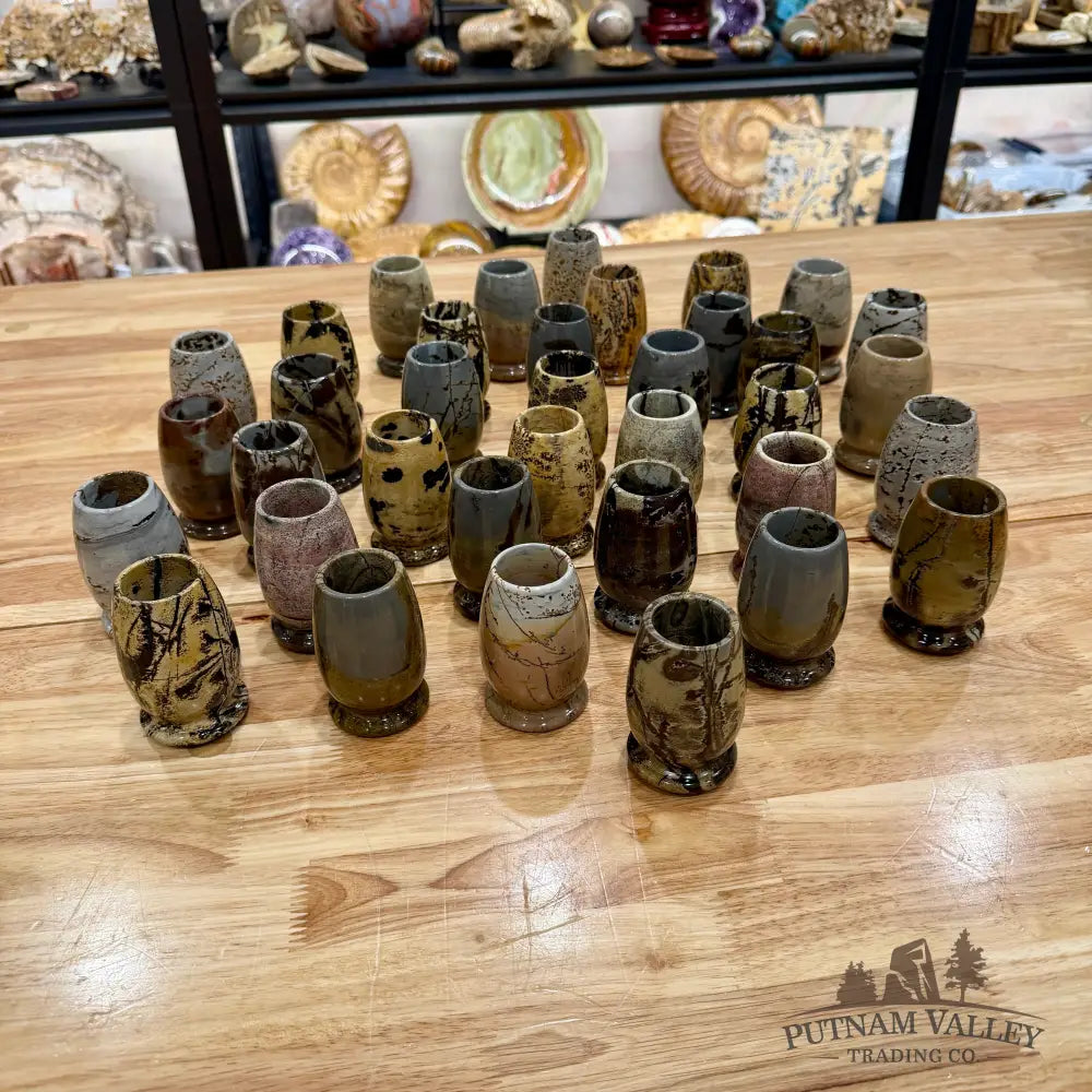 Collection of stone cups on a wooden table with shelves in the background